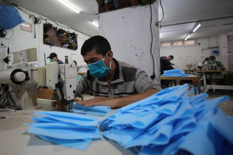 Protective clothing and mask production in Gaza- - GAZA CITY, GAZA - APRIL 12: Workers wearing masks produce protective clothing and masks in a textile factory in Gaza within fighting against coronavirus (Covid-19) pandemic to export them to West Bank and Israel in Gaza City, Gaza on April 12, 2020.