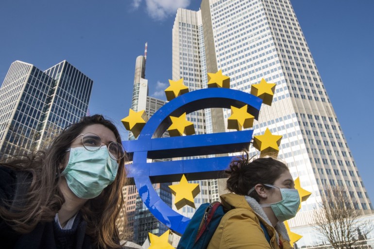 FRANKFURT AM MAIN, GERMANY - MARCH 19: Two students wear face mask while they pass the Euro sculpture with bicycles in the finance district on March 19, 2020 in Frankfurt, Germany. Restrictions from the state of Hesse have gone in force this week to stem the spread of the coronavirus (Covid-19) and that include the temporary shuttering of schools, public institutions and non-essential shops. Analysts see many banks as exposed to potential stress as a result of global disruptions caused by the virus. (Photo by Thomas Lohnes/Getty Images)