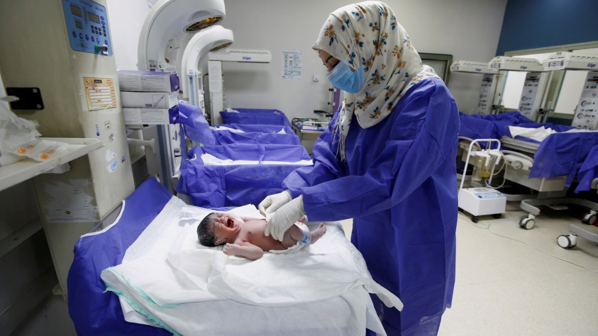 A nurse wearing a protective face mask and gloves to prevent the spread of coronavirus disease (COVID-19), takes care of a new born baby in a maternity room, in Najaf, Iraq April 2,2020. REUTERS/Alaa al-Marjani     TPX IMAGES OF THE DAY