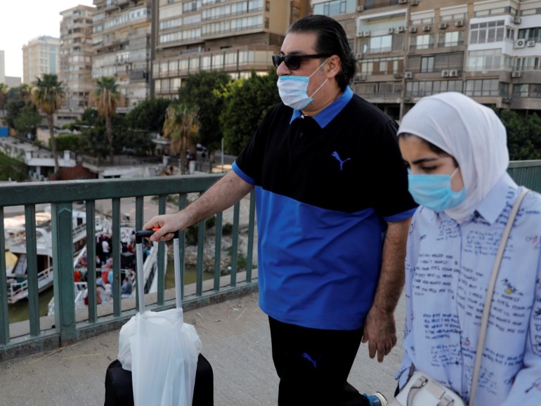 People wearing protective face masks due to the spread of coronavirus disease (COVID-19), pass near people who celebrate a wedding party on a yacht along the bank of the Nile rive before the start of a night-time curfew in Cairo, Egypt, April 2, 2020. REUTERS/Amr Abdallah Dalsh
