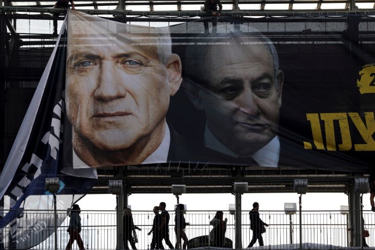 Labourers hang a banner depicting Benny Gantz, leader of Blue and White party, and Israel Prime minister Benjamin Netanyahu, as part of the party's campaign ahead of the upcoming election, in Tel Aviv, Israel February 17, 2020. REUTERS/Ammar Awad
