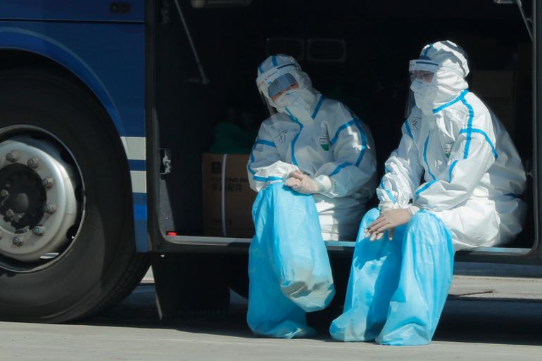 A nurse and doctor wearing protective face masks and suits rest in a bus next to the New China International Exhibition Center, which was converted into a transfer center for international inbound passengers, not far from the Capital International Airport, in Beijing, China, 19 March 2020