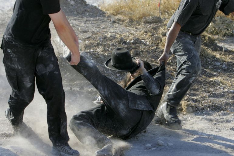 KIBBUTZ REGAVIM, ISRAEL - MAY 31: Israeli security guards drag an ultra-Orthodox Jew away from heavy machinery during a protest against the desecration of alleged ancient Jewish graves May 31, 2005 near Kibbutz Regavim in northern Israel. Dozens of black-garbed religious Jews clashed with the privately-hired guards as they tried to prevent the construction of the Trans-Israel highway over the graves. The protesters say the graves are Jewish, but archaeologists say they