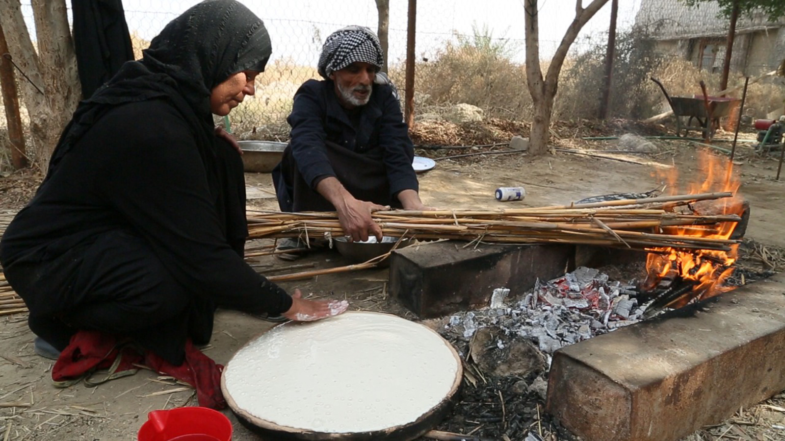 ‪عائلة أهوارية أثناء تحضير خبز الطابك‬ (الجزيرة)