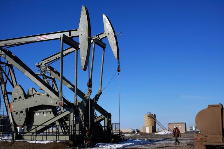 A man walks onto an oil drilling pump site in McKenzie County outside of Williston, North Dakota in this file photo from March 12, 2013. Several counties in North Dakota's Bakken formation and the Eagle Ford and Permian Basin of Texas have seen rig deployments or applications for new well permits drop in half, as energy companies are quickly steering drilling rigs away from marginal areas and focusing on sweet spots of U.S. shale oil fields.  REUTERS/Shannon Stapleton/