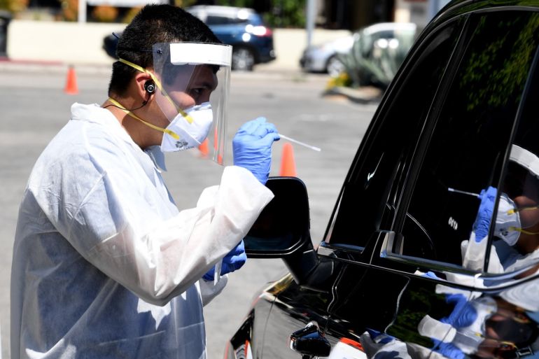 LOS ANGELES, CA - MAY 13: A worker wearing personal protective equipment (PPE) performs drive-up COVID-19 testing administered from a car at Mend Urgent Care testing site for the novel coronavirus at the Westfield Fashion Square on May 13, 2020 in the Sherman Oaks neighborhood of Los Angeles, California. A nasopharyngeal swab test kit is utilized at this COVID-19 testing center to determine the viral load and virus count of a patient. Los Angeles County 'safer at home' orders have been extended through August to stop the spread of coronavirus during the worldwide pandemic. Kevin Winter/ Getty Images/AFP== FOR NEWSPAPERS, INTERNET, TELCOS & TELEVISION USE ONLY ==