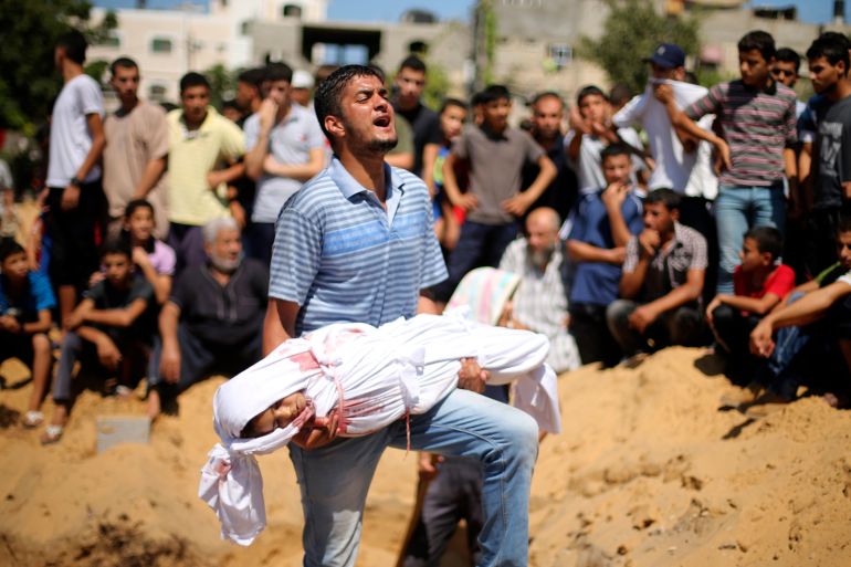 Palestinian man reacts as he carries the body of a girl from the Abu Nejim family, before her burial at a cemetery in Beit Lahiya in the northern Gaza Strip