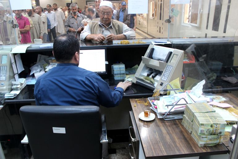 Libyan people gather in front of a counter in a bank to buy foreign currency in Misrata