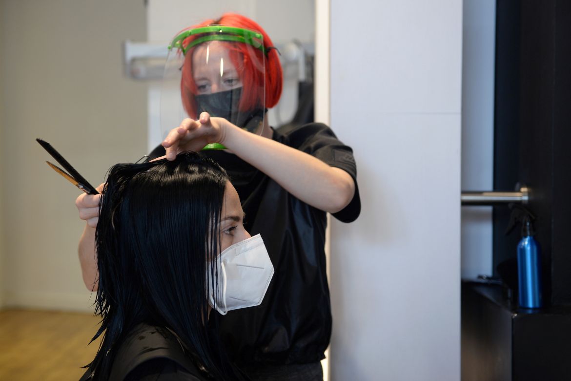 A hairdresser wearing a protective face mask cuts the hair of a customer following the outbreak of the coronavirus disease (COVID-19) in Brussels