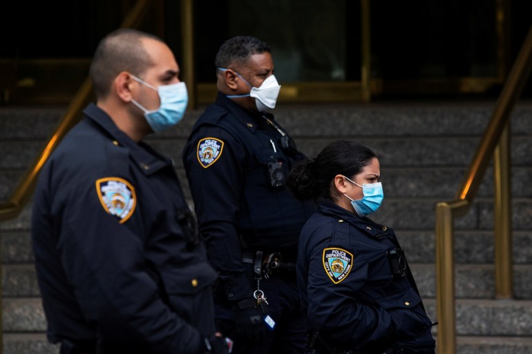 New York Police officers wear protective masks as they keep an eye on demonstrators who protest against U.S. President Donald Trump and his policies outside Trump International Hotel during the outbreak of the coronavirus disease (COVID19) in New York, U.S., April 18, 2020. REUTERS/Eduardo Munoz
