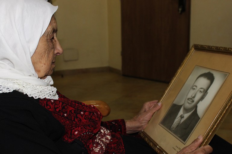 3-أسيل جندي، القدس، المسنة المقدسية تحمل صورة زوجها الذي توفي قبل عقود(الجزيرة نت)