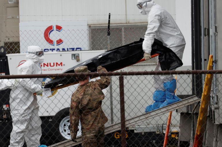 Workers wearing personal protective equipment (PPE) move the body of a deceased person from a refrigerated truck trailer set up at a temporary morgue outside University Hospital during the outbreak of the coronavirus disease (COVID-19) in Newark, New Jersey, U.S., May 6, 2020. REUTERS/Mike Segar