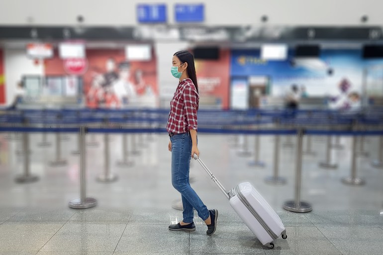 Asian tourist with luggage ,wearing mask to prevent during travel time at the airport terminal for protect from the new Coronavirus 2019 infection outbreak situation