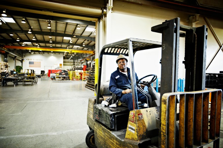 Steel worker driving forklift in steel manufacturing facility