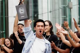 Surrounded by cheering Apple Store employees, one of the first iPhone buyers leaves the store on Fifth Avenue in New York
