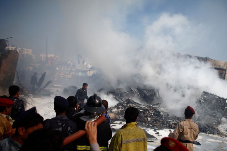 Army and police officers examine the wreckage of a plane after it crashed in Sanaa