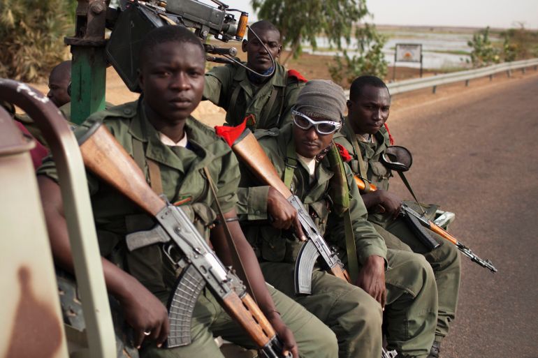 Malian soldiers ride in the back of a military pickup truck in Gao
