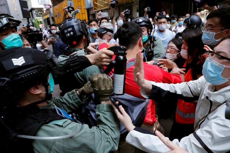 Anti-government demonstrators scuffle with riot police during a lunch time protest as a second reading of a controversial national anthem law takes place in Hong Kong