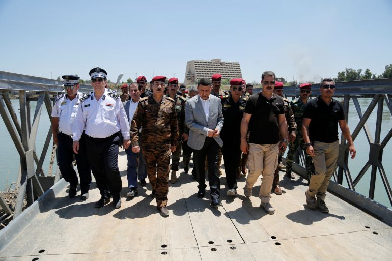 Najm al-Jabouri walks next to Mansour Mareid during a visit to one of Mosul's temporary bridges in Mosul