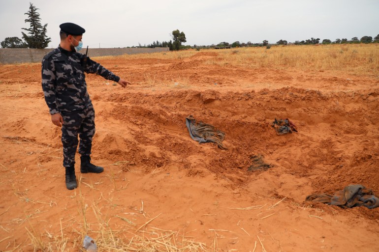 A member of security forces loyal to Libya's internationally recognised government points to a mass grave, according to Libya's Internationally recognised government officials, in Tarhouna city