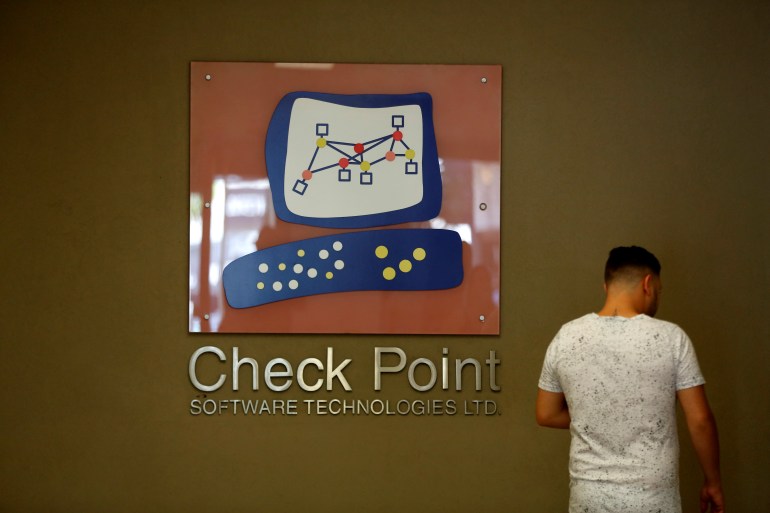 A man stands next to the logo of network security provider Check Point Software Technologies Ltd, at their headquarters in Tel Aviv, Israel (رويترز)