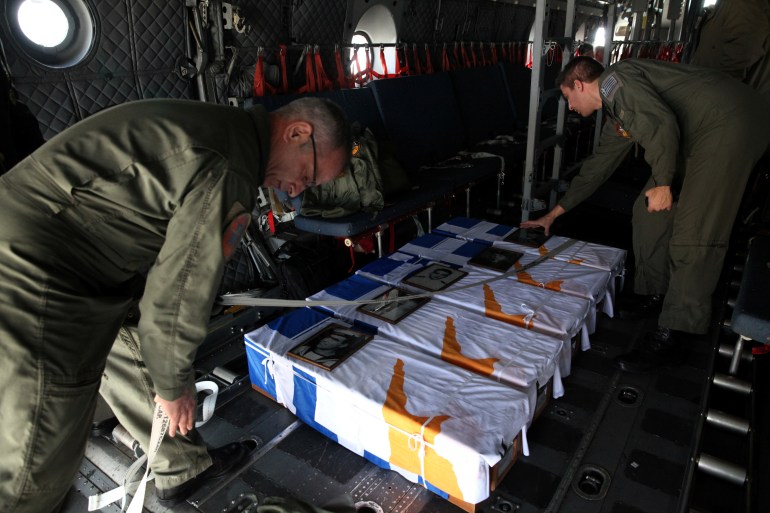 Soldiers set up the caskets of soldiers who died in August 1964 while onboard the patrol boat Phaethon in the Tyllirias area of the island, when it was bombed by a Turkish aircraft, during a ceremony at Larnaca International Airport