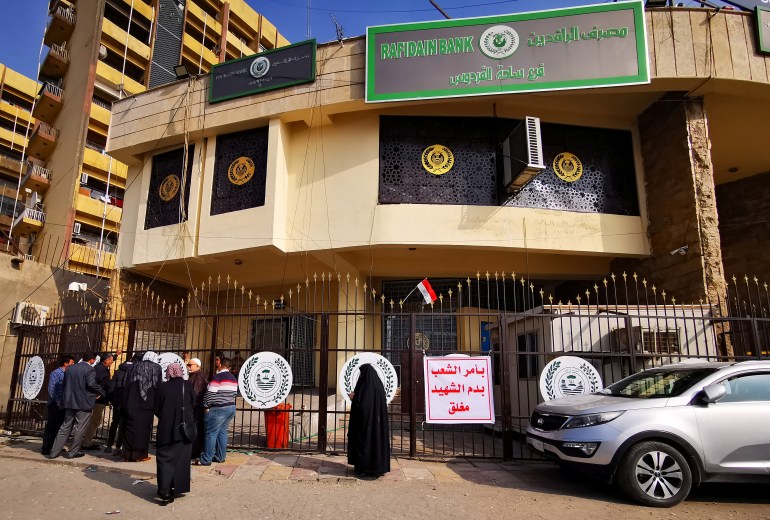 Customers gather outside a bank after it was closed during a nationwide strike, in Baghdad (رويترز)