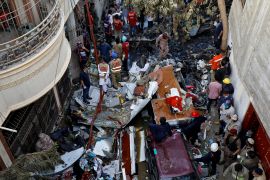 Rescue workers gather at the site of a passenger plane crash in a residential area near an airport in Karachi