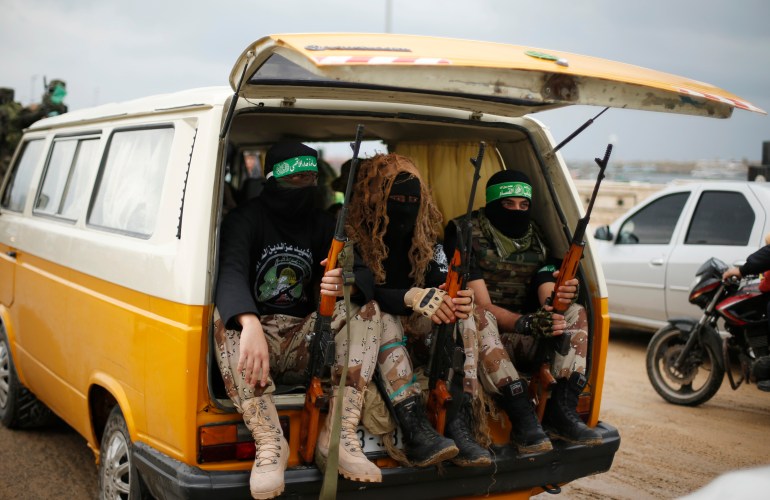 Palestinian members of al-Qassam Brigades, the armed wing of the Hamas movement, sit in a vehicle as they take part in a military parade in Gaza City