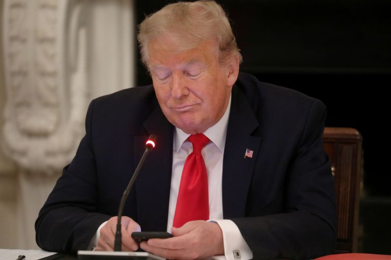 U.S. President Trump uses phone during roundtable discussion on the reopening of U.S. economy at the White House in Washington