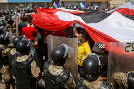Iraqi security forces stand in front of demonstrators in anti-government protests during Iraqi Prime Minister Mustafa al-Kadhimi's visit, in Basra