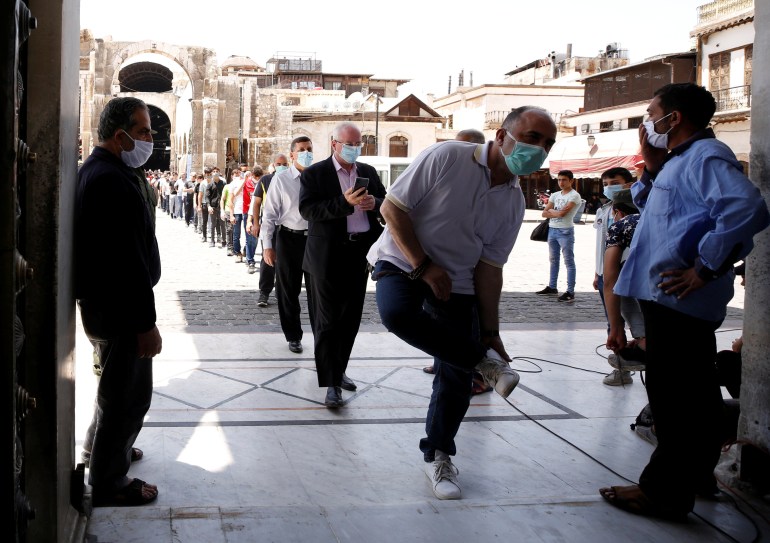 People wear face masks as they wait in line to enter and attend the Friday prayers, after the government eased the restrictions amid concerns over the coronavirus disease (COVID-19) outbreak, at Umayyad mosque in Damascus