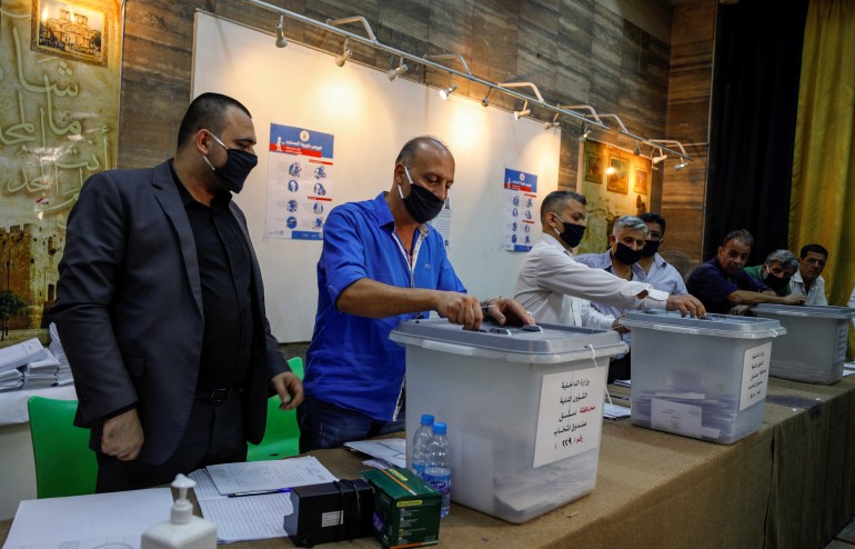 Men prepare to open ballot boxes at a polling station to start the counting process during parliamentary election in Damascus