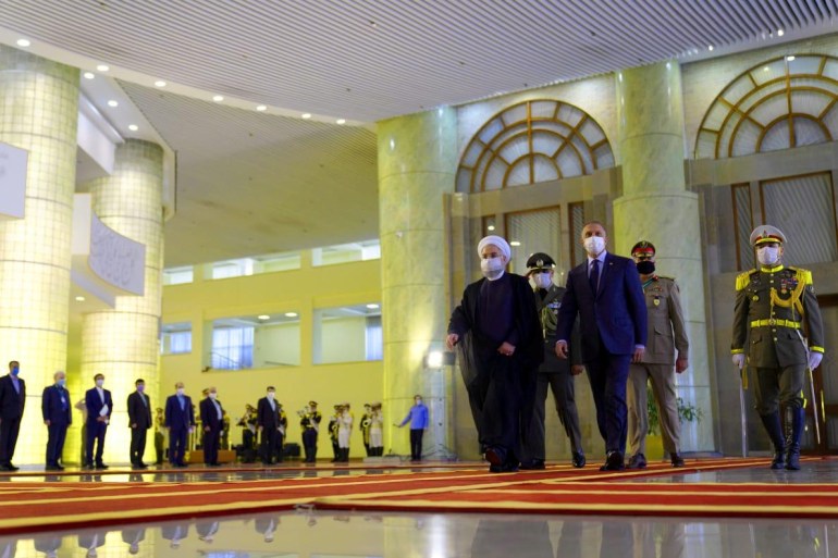 Iranian President Hassan Rouhani welcomes Iraqi Prime Minister Mustafa al-Kadhimi as they wear protective masks, in Tehran