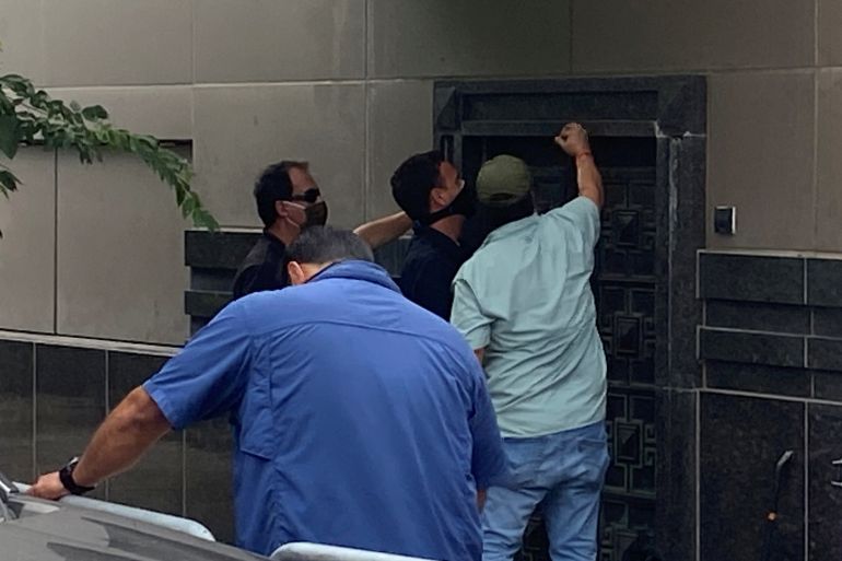A group of people use power tools to try to pry open a rear door of the Chinese consulate in Housto
