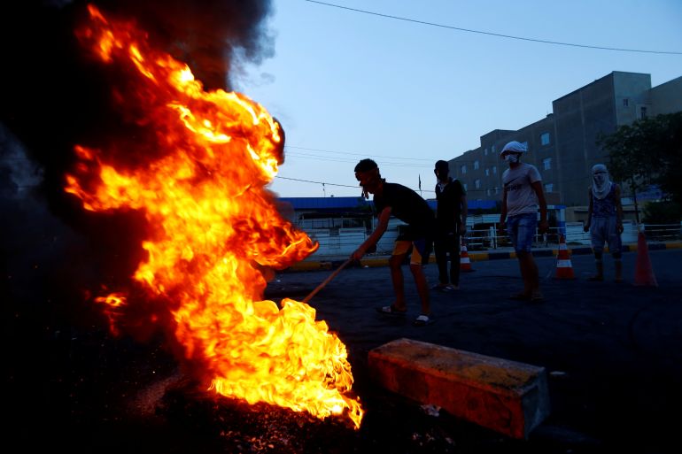 Iraqi demonstrators burn tires to block the road during a protest over poor public services in the holy city of Najaf