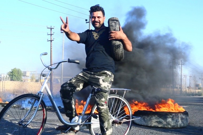 متظاهر في شمال الناصرية وهو يحرق الاطارات احتجاجا على غياب الخدمات (الجزيرة)