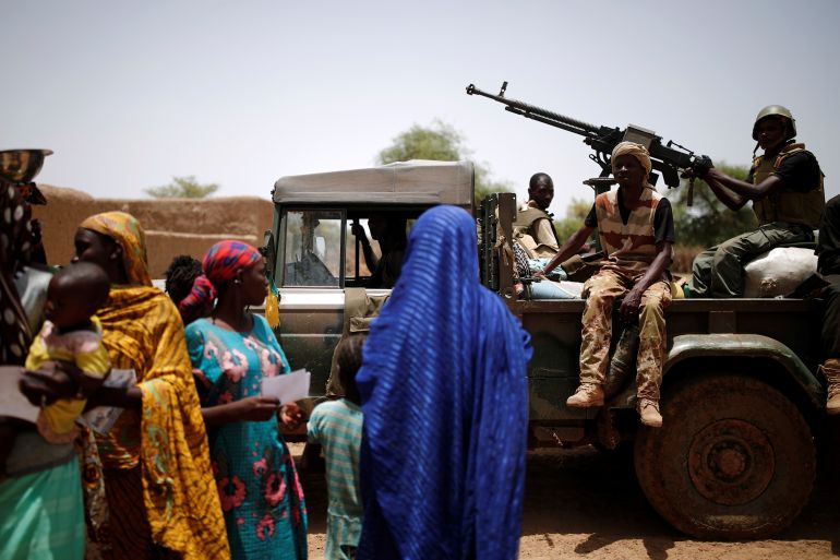 Malian Armed Forces (FAMa) soldiers drive along women and children during the Operation Barkhane in Ndaki