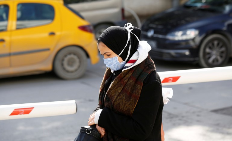 Woman wears a protective face mask as she walks in Tunis