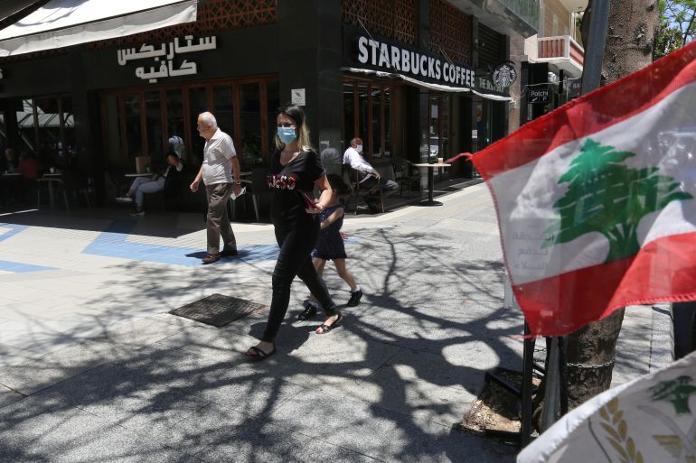 A woman wearing a protective face mask walks past a Starbucks coffee shop in Hamra street in Beirut