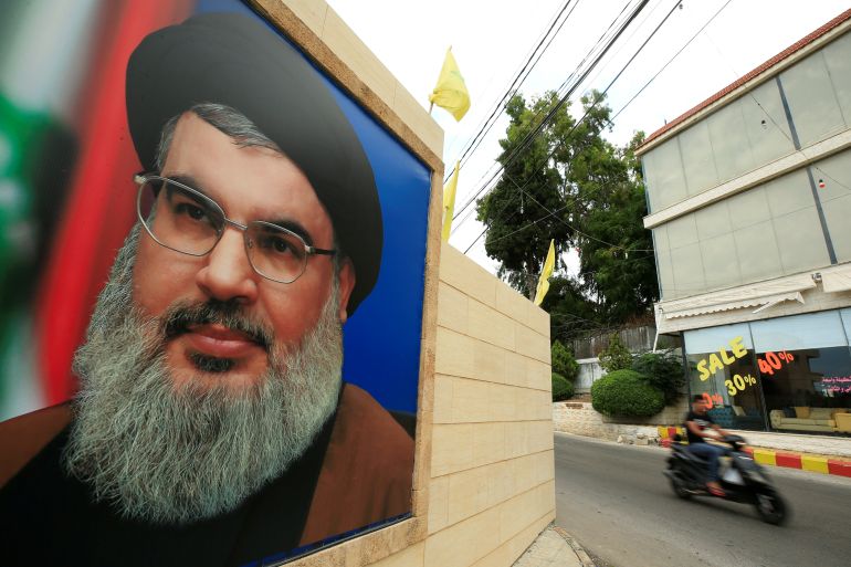 A man rides a motorbike past a picture of Lebanon's Hezbollah leader Sayyed Hassan Nasrallah, near Sidon