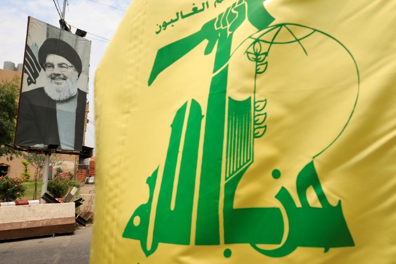 A Hezbollah flag and a poster depicting Lebanon's Hezbollah leader Sayyed Hassan Nasrallah are pictured along a street, near Sidon