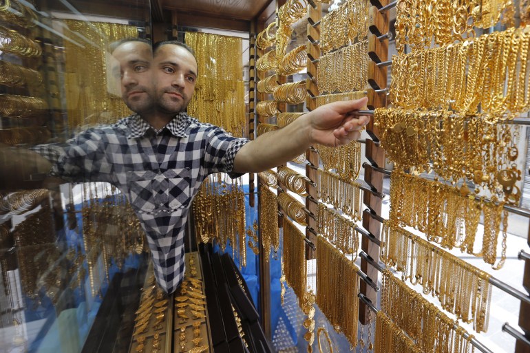 A Jordanian goldsmith places gold chains for display at his jewellery shop in Amman