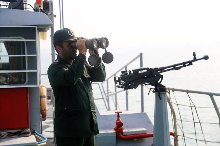 An IRGC officer looks through binoculars on a boat in coastal water during the annual military parade in Bandar Abbas