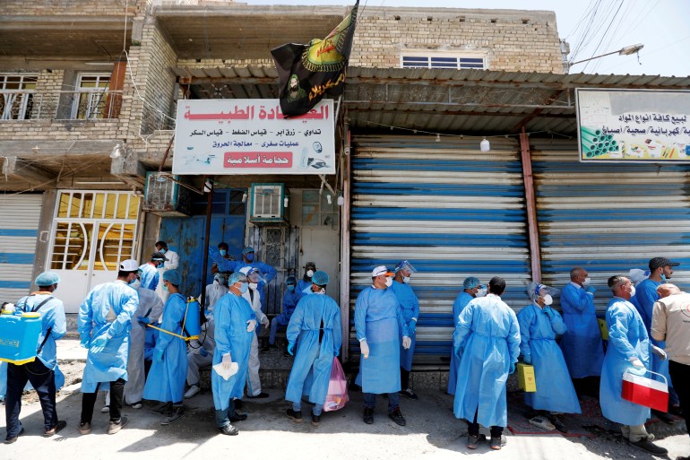 Healthcare workers gather in a street during testing for the coronavirus disease (COVID-19) in Sadr city, district of Baghdad