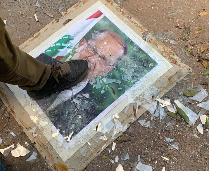 A demonstrator steps on a picture of Lebanese President Michel Aoun, at the Ministry of Foreign Affairs during a protest following Tuesday's blast, in Beirut