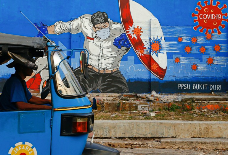 A rickshaw taxi passes a mural promoting awareness of the coronavirus disease (COVID-19) outbreak in Jakarta
