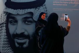 Participants take photos next to a picture of Saudi Crown Prince Mohammed bin Salman during the Misk Global Forum in Riyadh