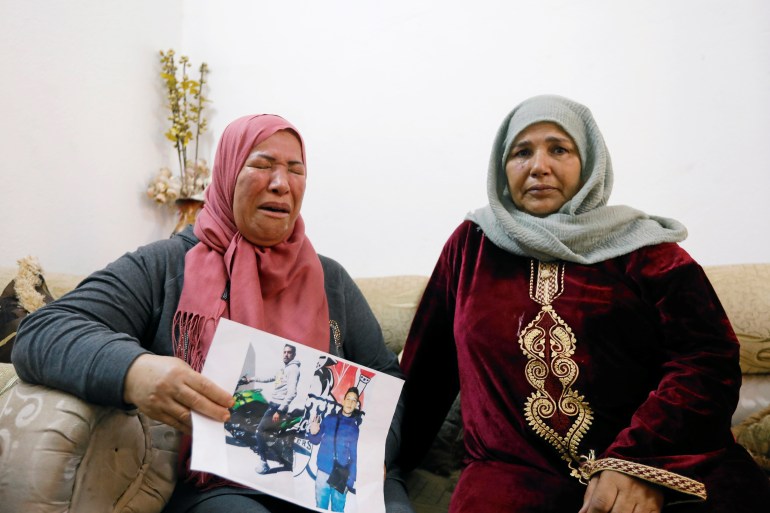 Zakia, mother of Fakher Hmidi, carries his pictures as she reacts during an interview with Reuters in Thina district of Sfax