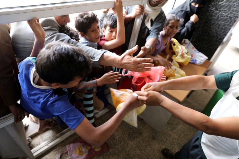 People crowd to get food rations from a charity kitchen in Sanaa